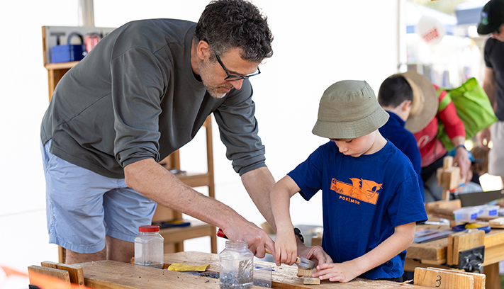 A father and son engage in some woodworking.