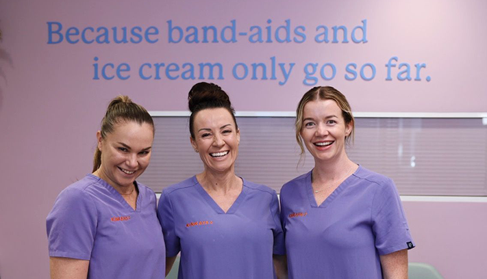 Three medical professionals laughing and smiling with each other.