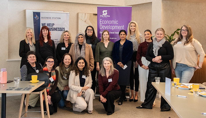 Group photo of participants at a business networking and economic development workshop, standing in front of event banners.