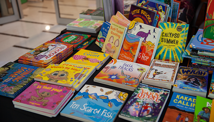 Display table featuring a wide selection of children’s books by Aboriginal and Torres Strait Islander authors and illustrators in a library or community setting.