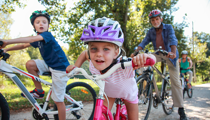 A multigenerational family riding bikes on a gravel path.
