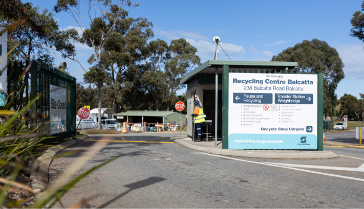 Entrance to the Recycling Centre Balcatta, with signage, a gatehouse and a staff member at the site entrance.