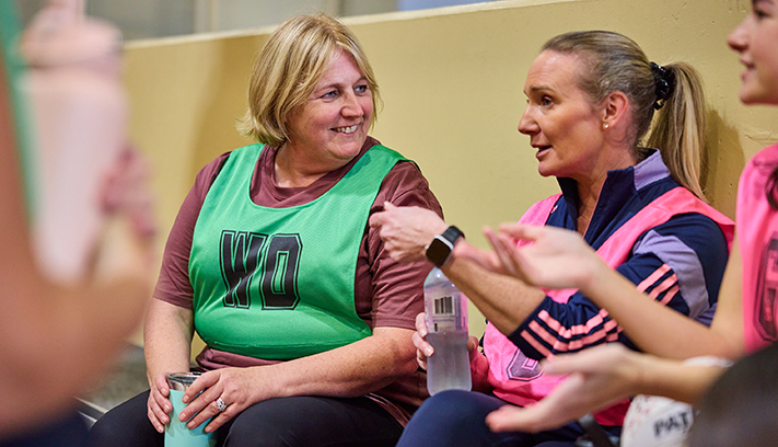 Netball players resting on the bench.