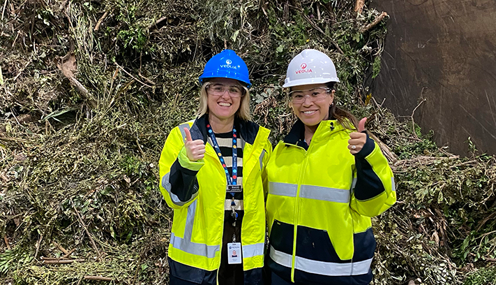 Two female City officers give the thumbs up in front of a pile of green waste.
