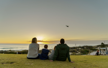 A family watches the sunset from a hillside.