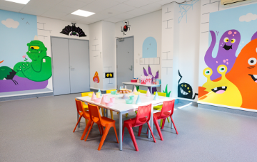 Children’s party room with colourful monster murals, child-sized tables and chairs, and party decorations.