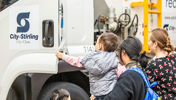 A young family looks into the cabin of a City of Stirling rubbish truck.