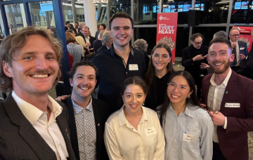 Group of people posing for a photo at a networking event, with attendees mingling and Heart Foundation banners visible in the background.