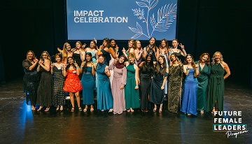 Group photo of participants on stage at a Future Female Leaders Program Impact Celebration event, standing in front of a large presentation screen.