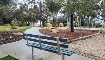 Park reserve featuring a winding shared path, bench seating and a nature-based playground among mature trees and landscaped garden beds.