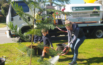 Mother and son water their new street tree.