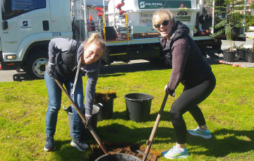 Two sisters digging a hole for a tree.