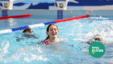 Children participating in a swimming lesson at an outdoor pool, with Stirling Extras branding displayed in the corner.