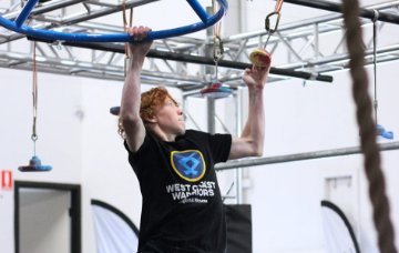 A young person holds onto a spinning bar and a small resin hold.