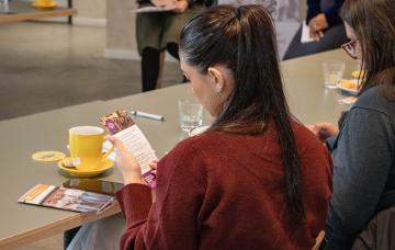 Person selecting a pastry from a catering table with croissants, plates and glassware at a business networking event.