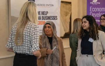 Participants networking at a business workshop in front of Business Station and Economic Development event banners.