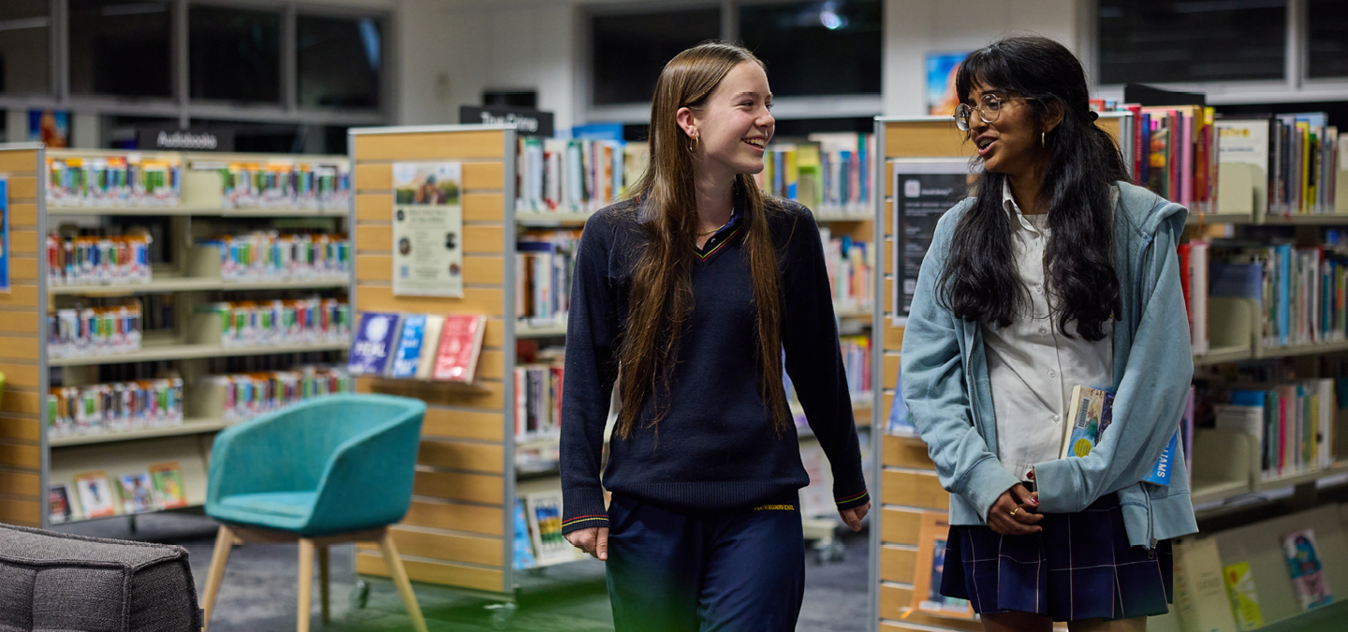 Two teens walking in a library